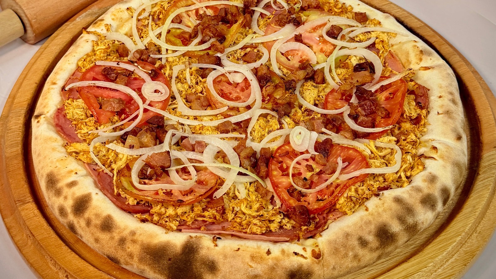 Pizza Du chefe da Castro's Pizza na tábua, com frango, presunto, bacon, tomate e cebola